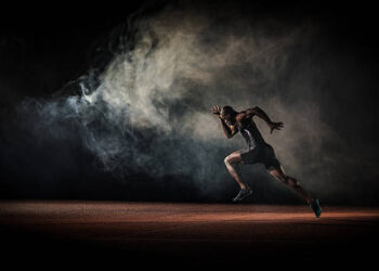 Young male athlete running on race track.