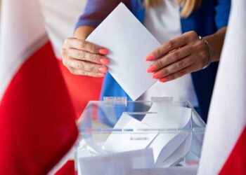 Woman putting her vote to ballot box. Poland political elections