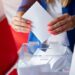 Woman putting her vote to ballot box. Poland political elections