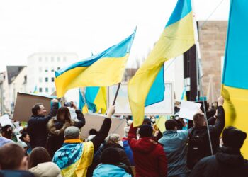 people gathering on street holding ukraine flags